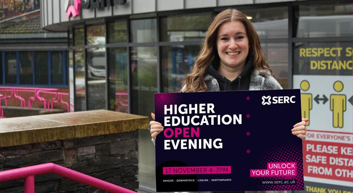 Zara Shaw outside SERC's Bangor campus with a board displaying the HE Open Evening Graphic